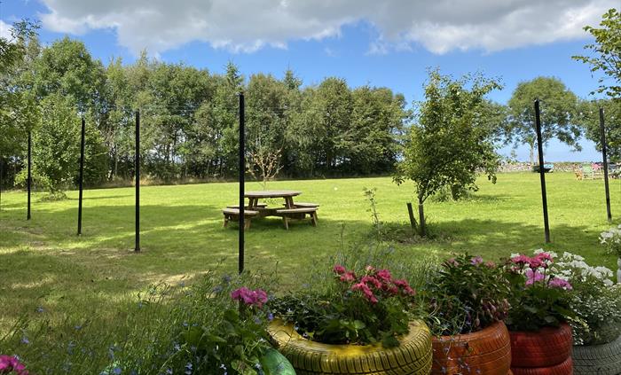 Green lawn for play and event space with colourful tiers, flower and picnic tables